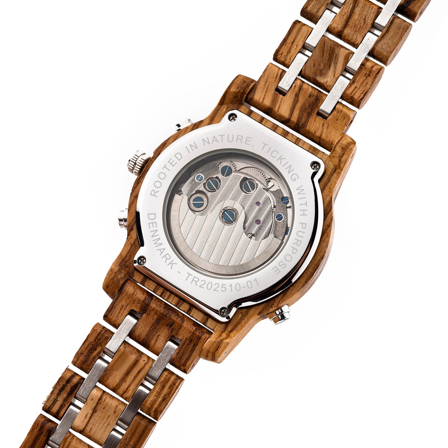 Back of a wooden wristwatch with visible mechanical movement and inscription 'Rooted in nature, ticking with purpose'