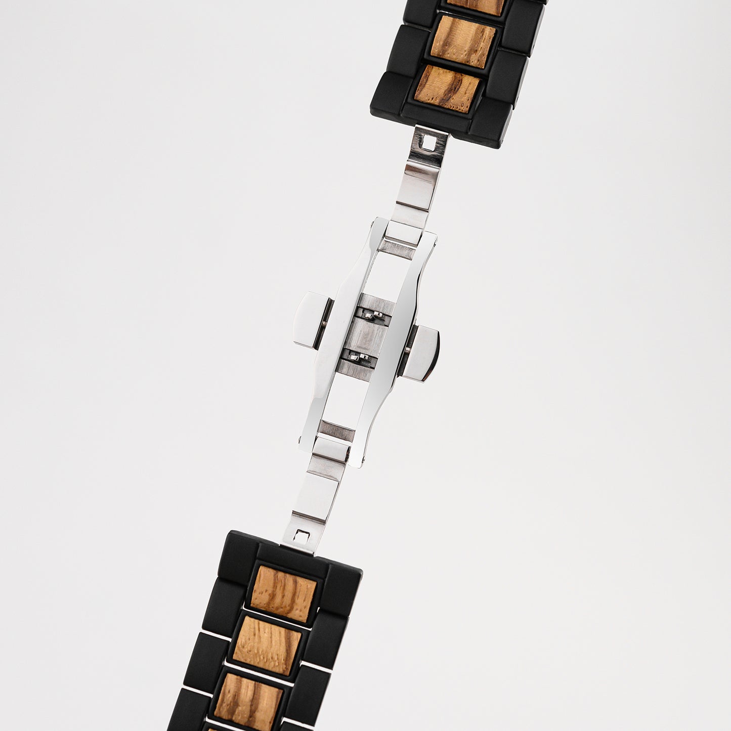 Close-up of black and wood link watch band with silver clasp on white background