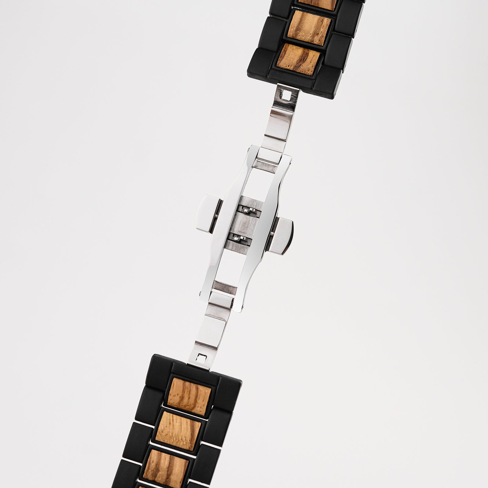 Close-up of black and wood link watch band with silver clasp on white background