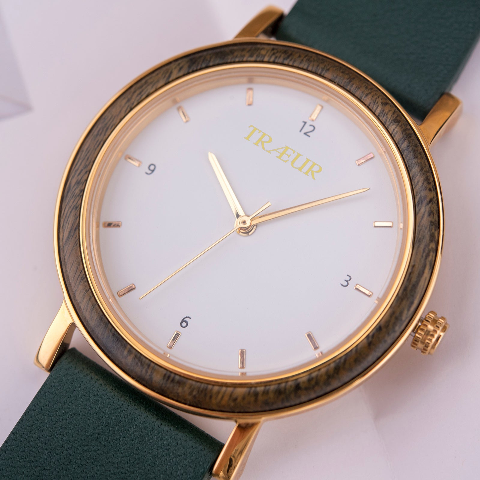 Elegant Træur wristwatch with gold case, wood-textured bezel, white dial, and green leather strap