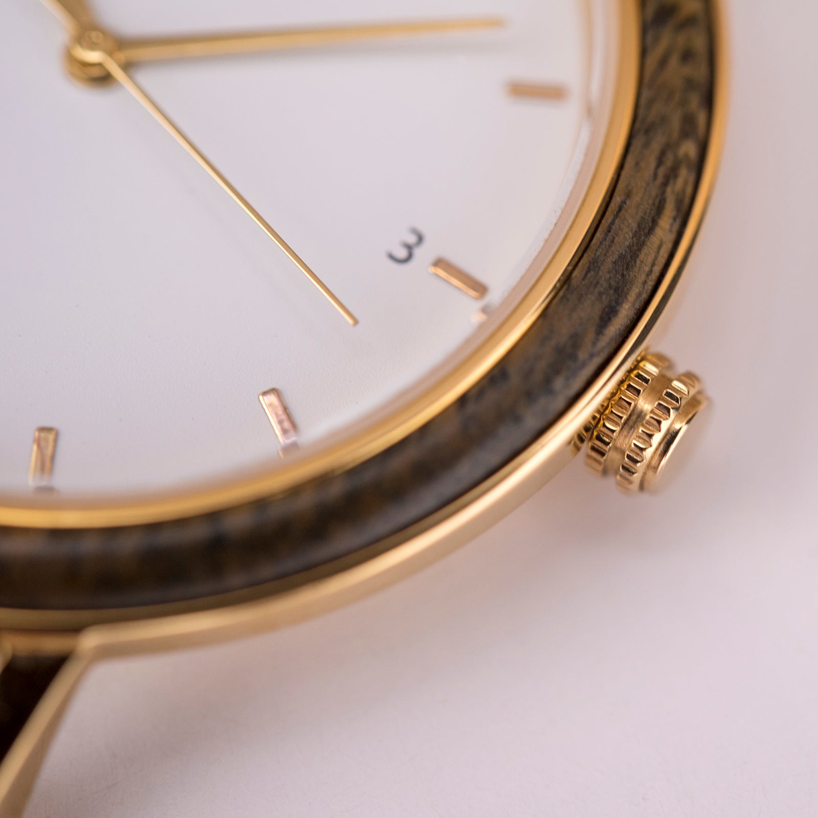 Close-up of elegant wristwatch with gold accents and white dial showing hour markers and crown