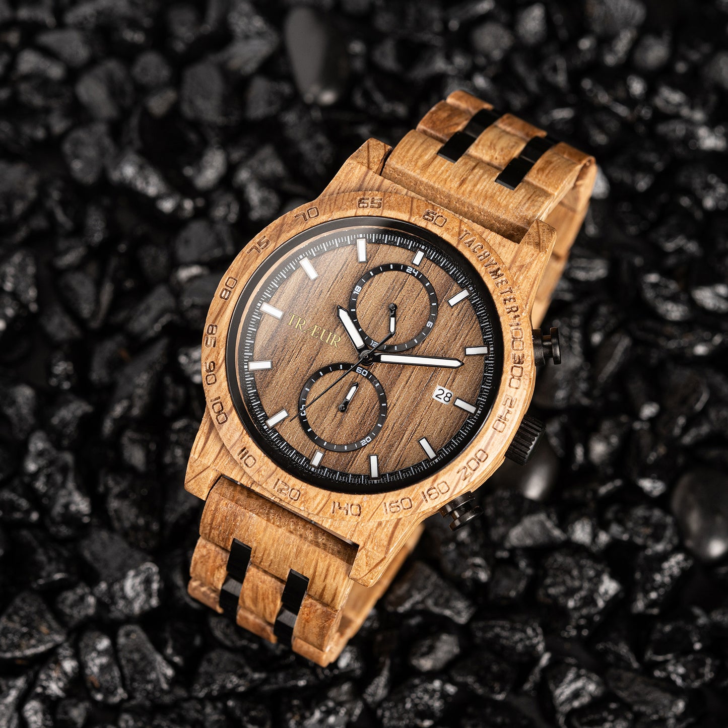 Wooden wristwatch with black accents on dark textured stone background, tachymeter dial