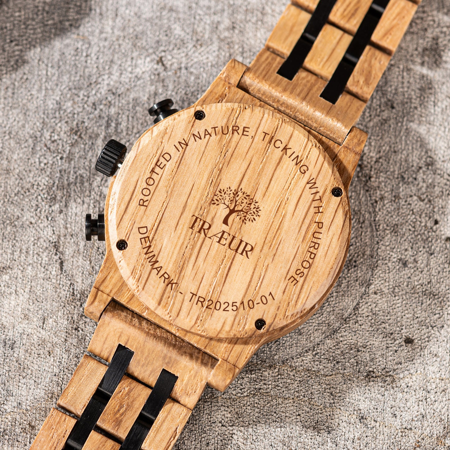 Close-up of engraved wooden back of Traeur watch with natural grain and black metal accents