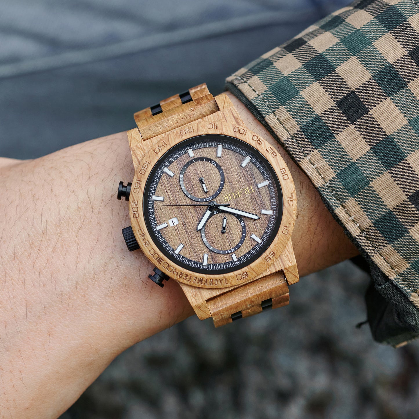 wooden wristwatch with chronograph and tachymeter on wrist wearing green plaid shirt