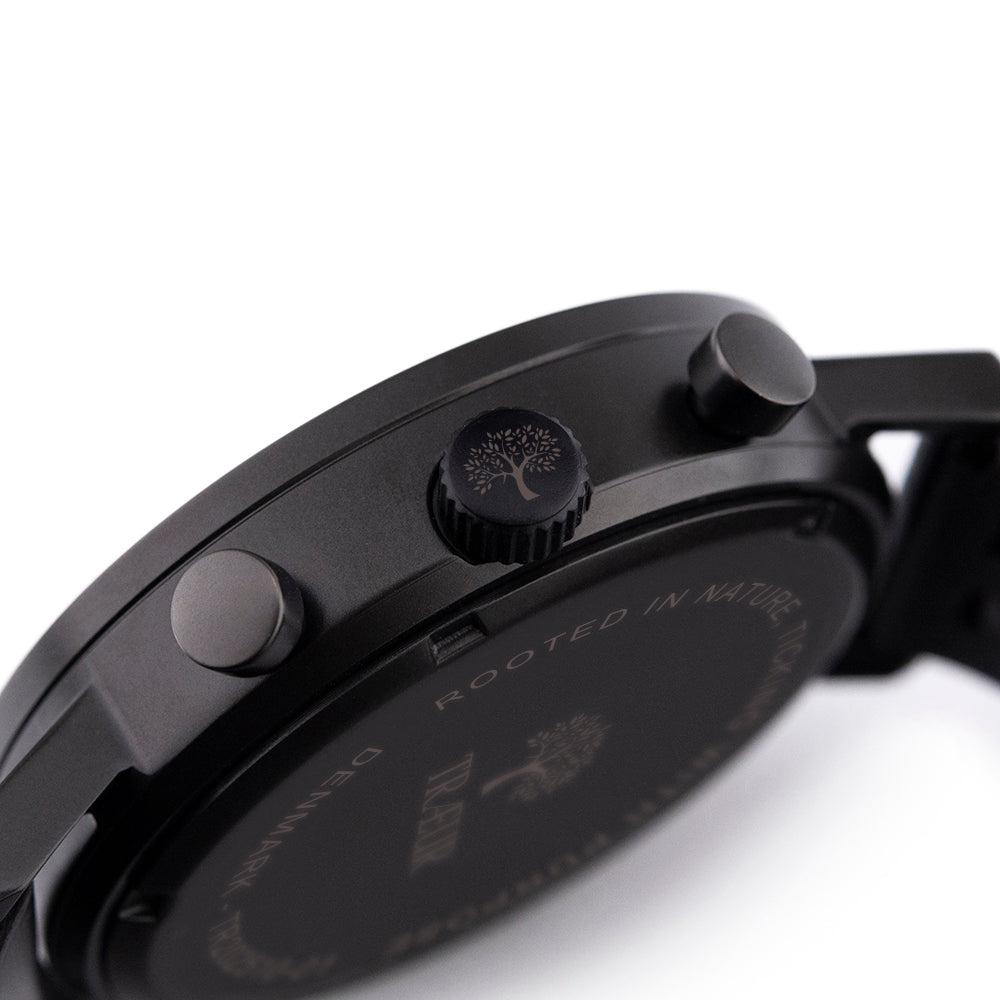 Close-up of black wristwatch side with engraved tree logo on crown and two buttons