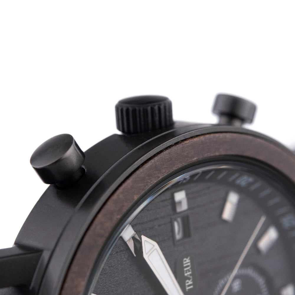 Close-up of black chronograph watch with wooden bezel and textured dial showing TRAEUR branding