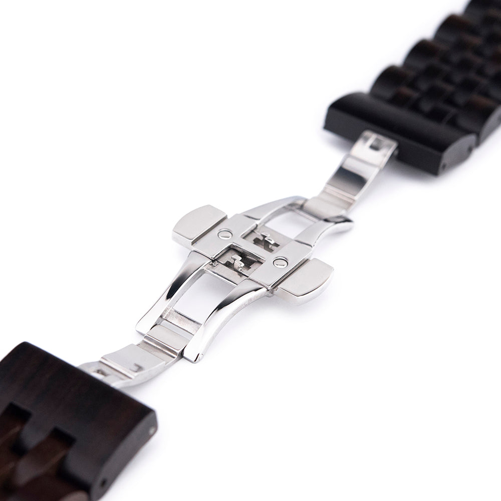 Close-up of silver metal butterfly clasp on dark wooden watch band on white background